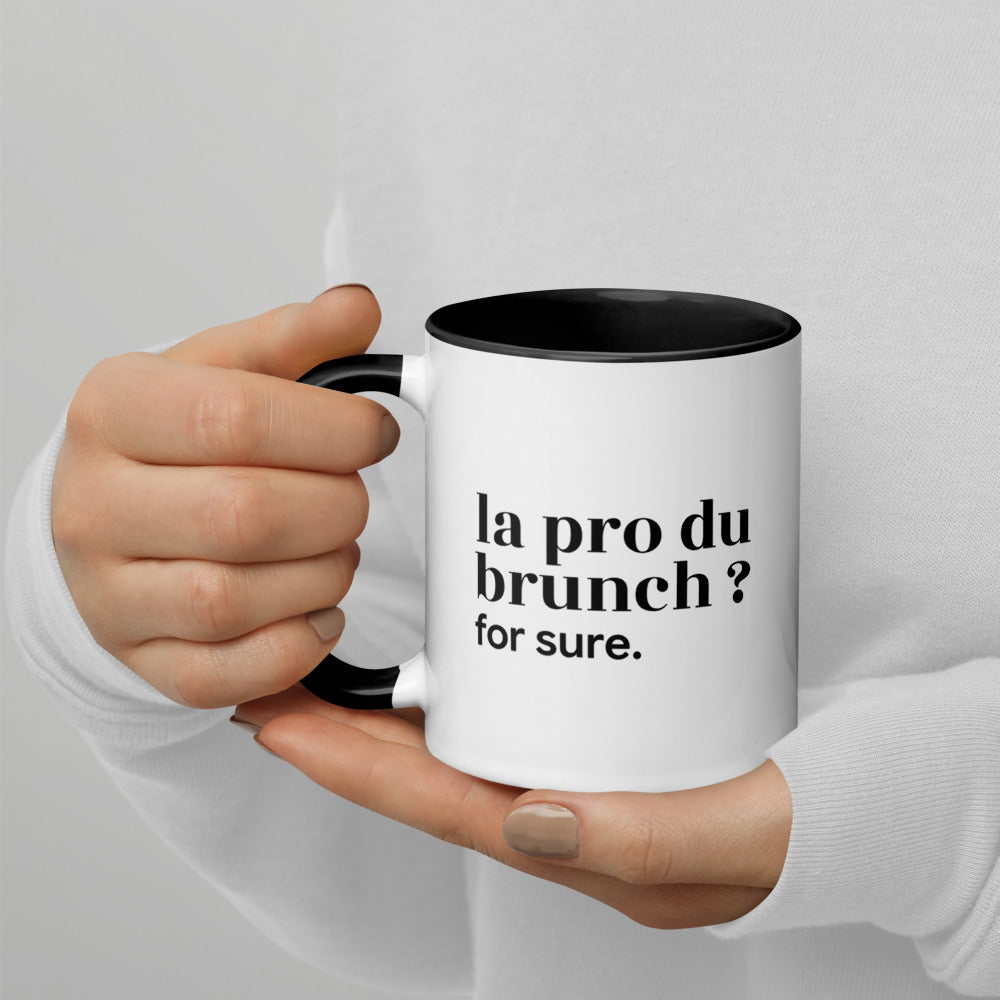 Mug intérieur noir « la pro du brunch ? for sure. », tenu dans les mains