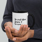 Mug intérieur noir « le roi des jeux ? for sure. », tenu dans les mains