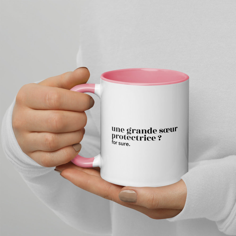 Mug intérieur rose « une grande sœur protectrice ? for sure. », tenu dans les mains