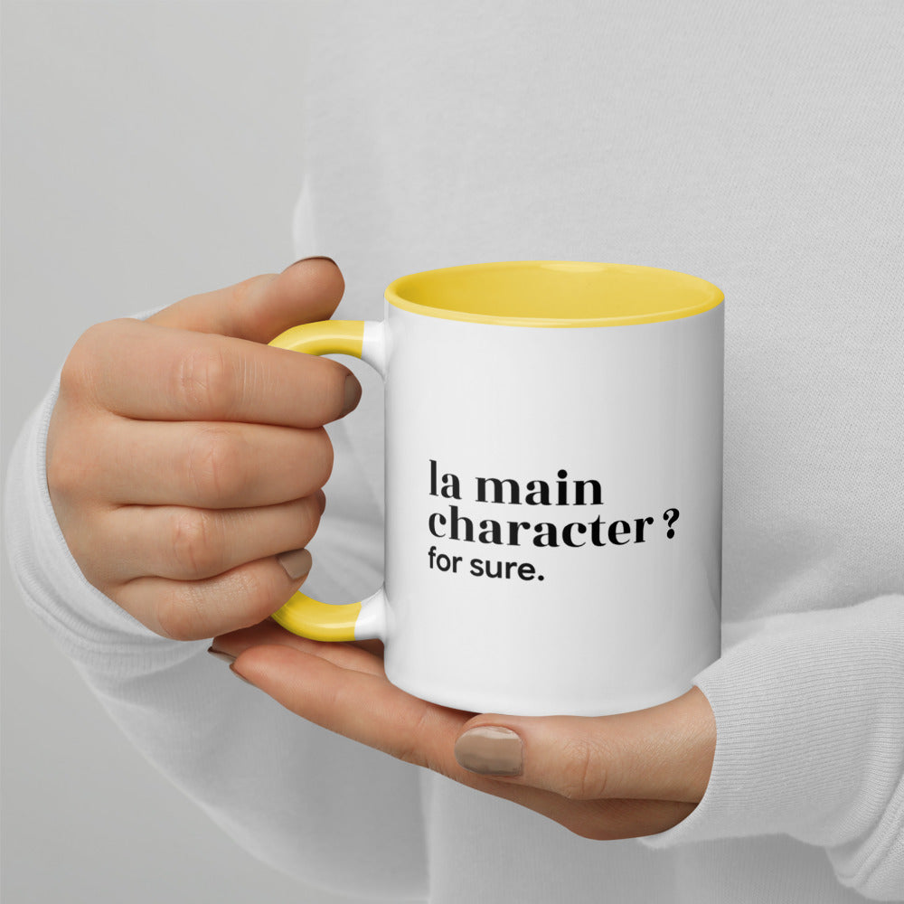 Mug intérieur jaune « la main character ? for sure. », tenu dans les mains
