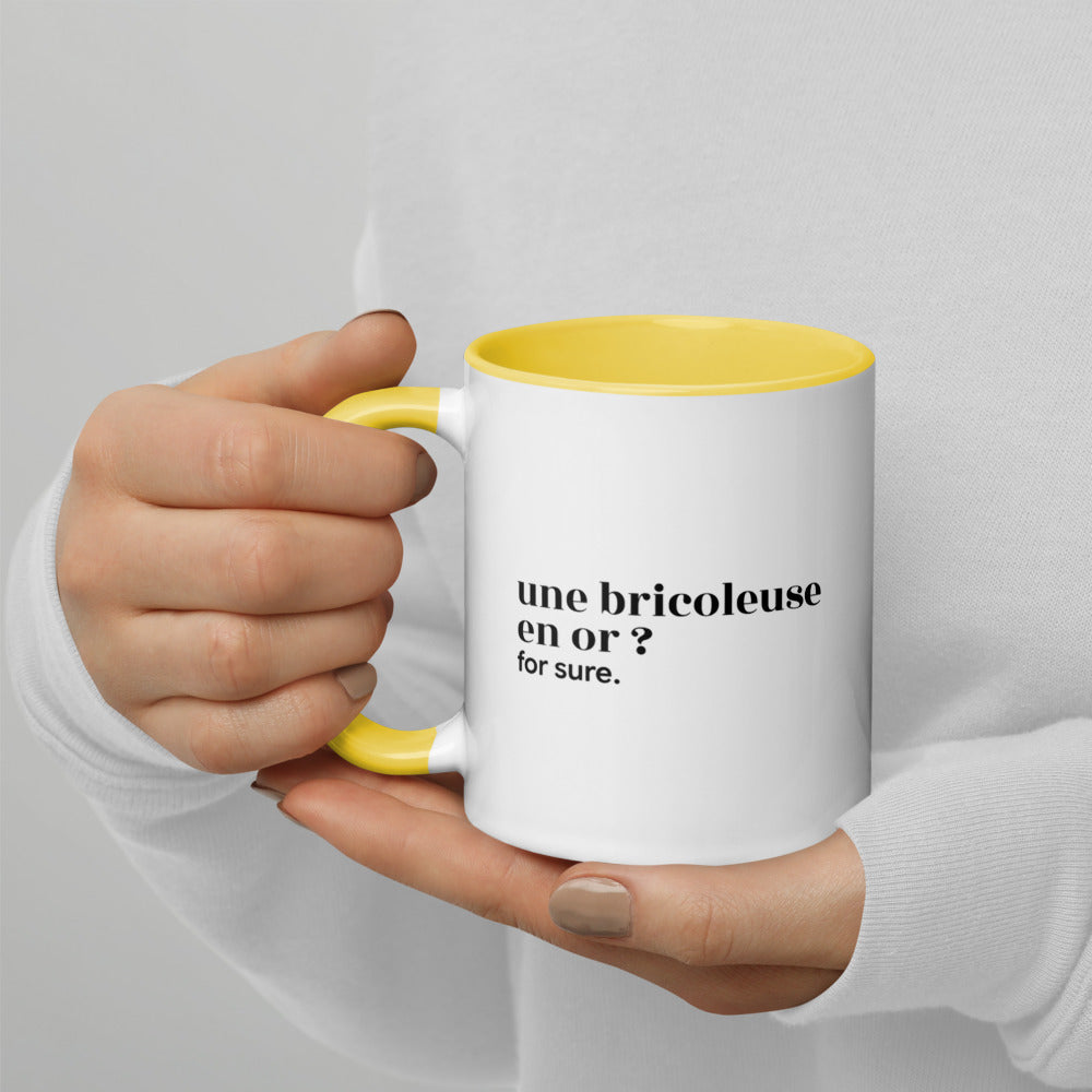 Mug intérieur jaune « une bricoleuse en or ? for sure. », tenu dans les mains