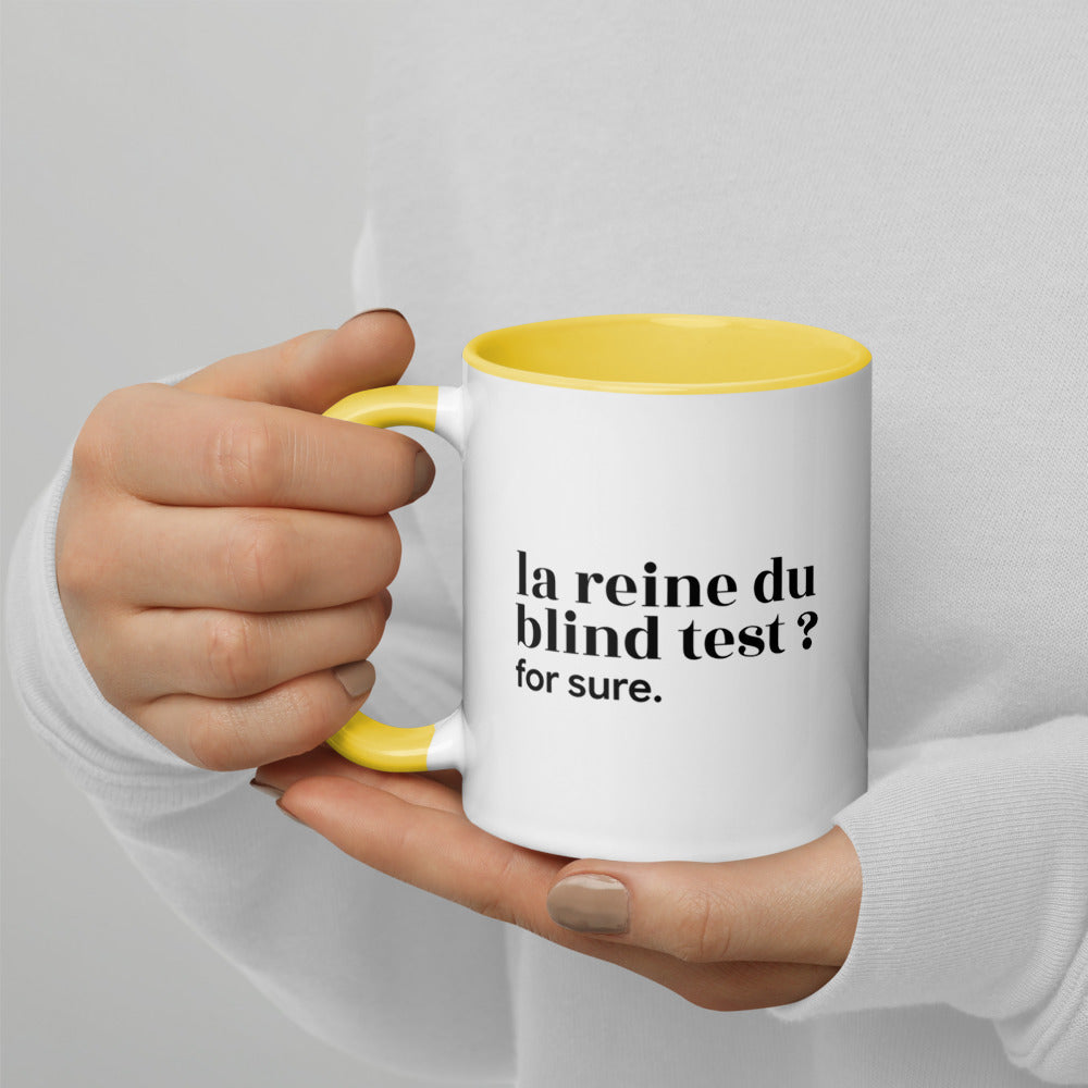 Mug intérieur jaune « la reine du blind test ? for sure. », tenu dans les mains