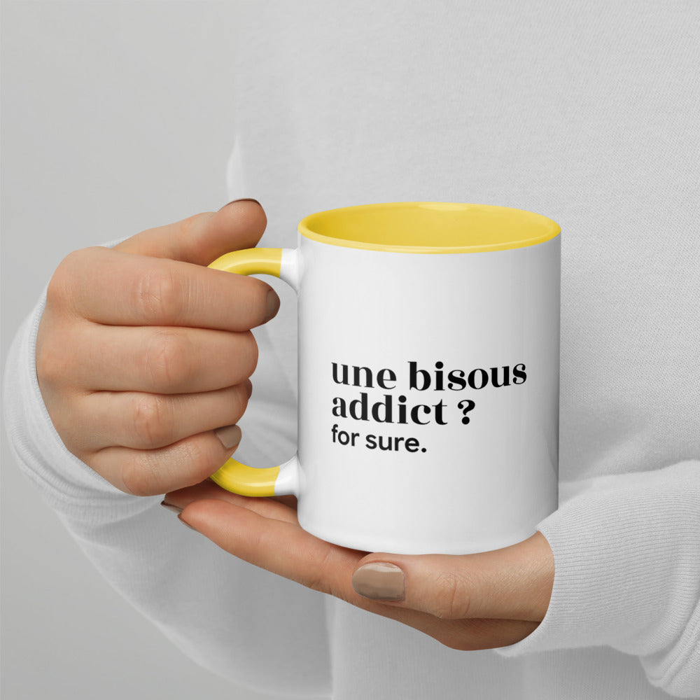 Mug intérieur jaune « une bisous addict ? for sure. », tenu dans les mains