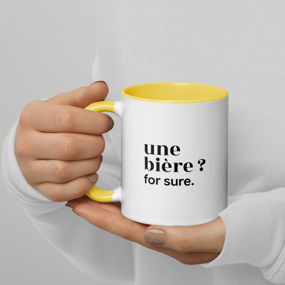 Mug intérieur jaune « une bière ? for sure. », tenu dans les mains