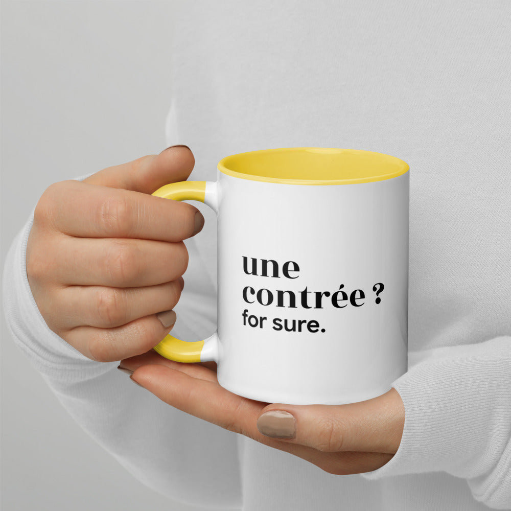 Mug intérieur jaune « une contrée ? for sure. », tenu dans les mains