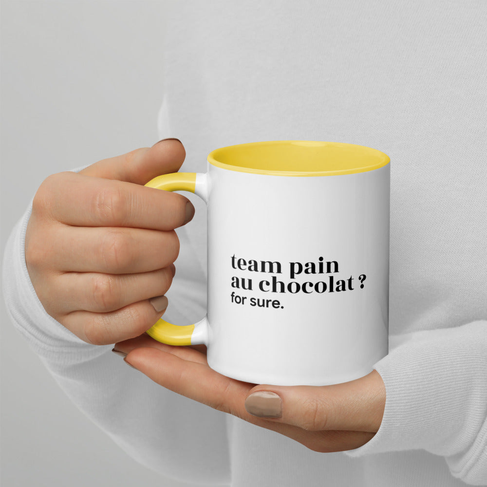 Mug intérieur jaune « team pain au chocolat ? for sure. », tenu dans les mains
