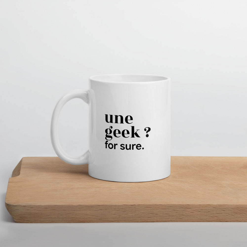 Mug blanc « une geek ? for sure. », sur une planche en bois