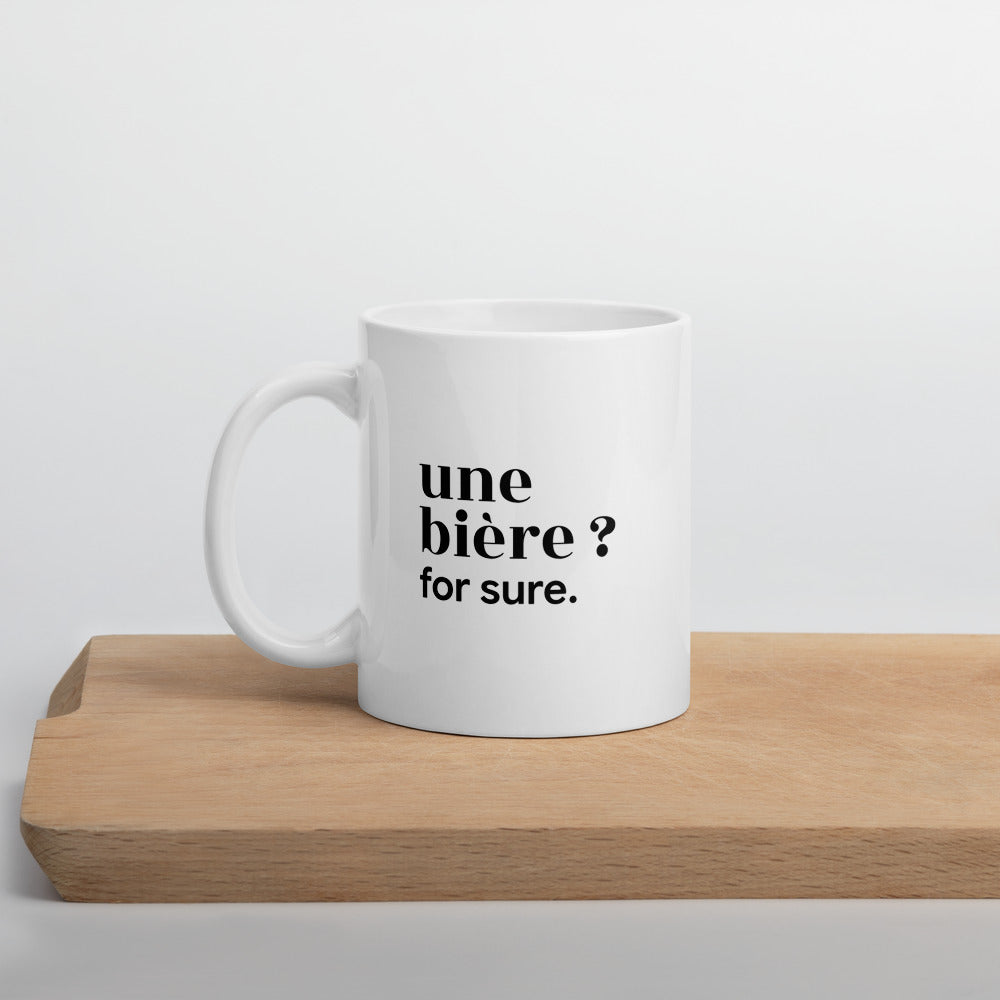 Mug blanc « une bière ? for sure. », sur une planche en bois