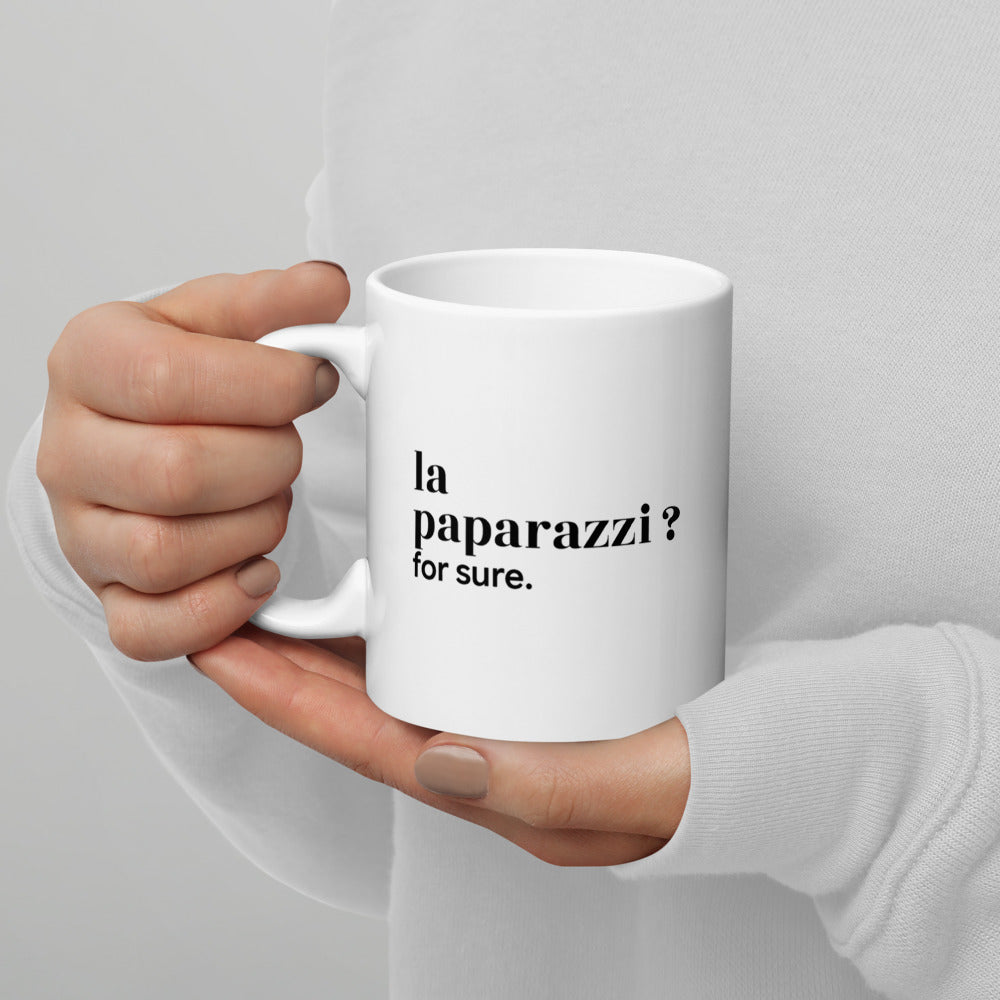 Mug blanc « la paparazzi ? for sure. », tenu dans les mains