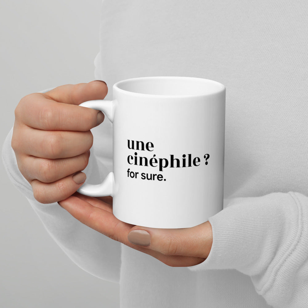 Mug blanc « une cinéphile ? for sure. », tenu dans les mains