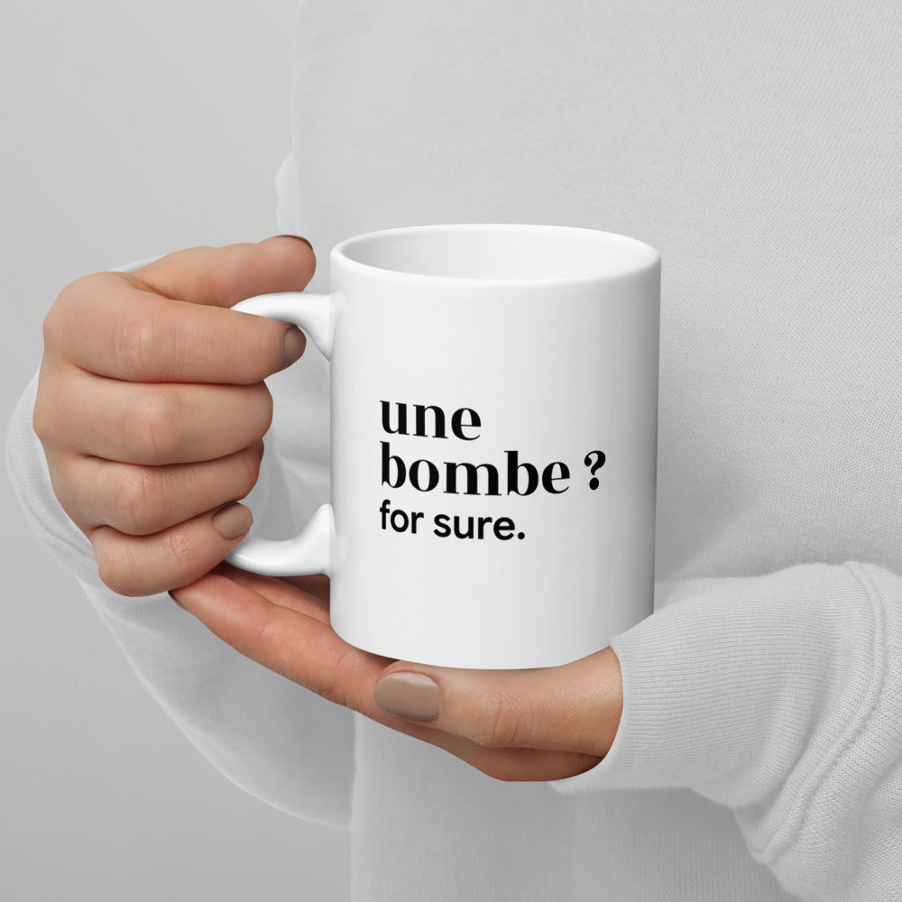 Mug blanc « une bombe ? for sure. », tenu dans les mains