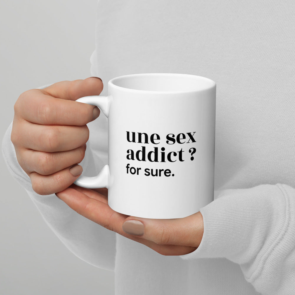 Mug blanc « une sex addict ? for sure. », tenu dans les mains
