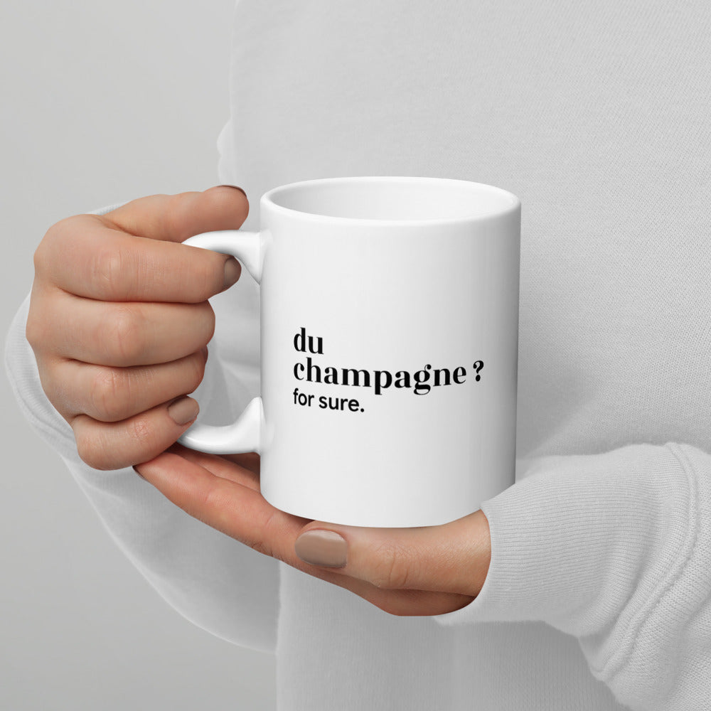 Mug blanc « du champagne ? for sure. », tenu dans les mains