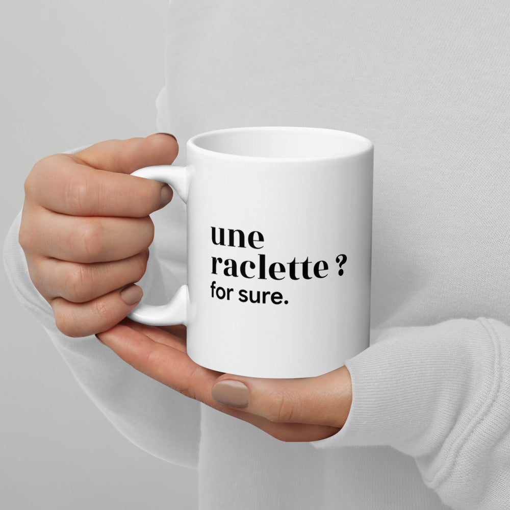 Mug blanc « une raclette ? for sure. », tenu dans les mains